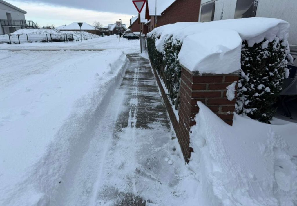 Eine Straße mit geräumtem Gehweg. der Schnee liegt aufgetürmt am Rand.