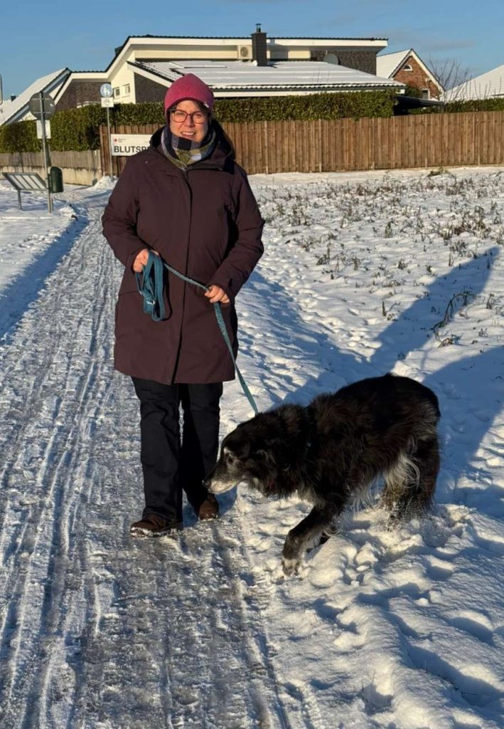 Sabine Landua mit Hund beim Winterspaziergang in der Sonne.