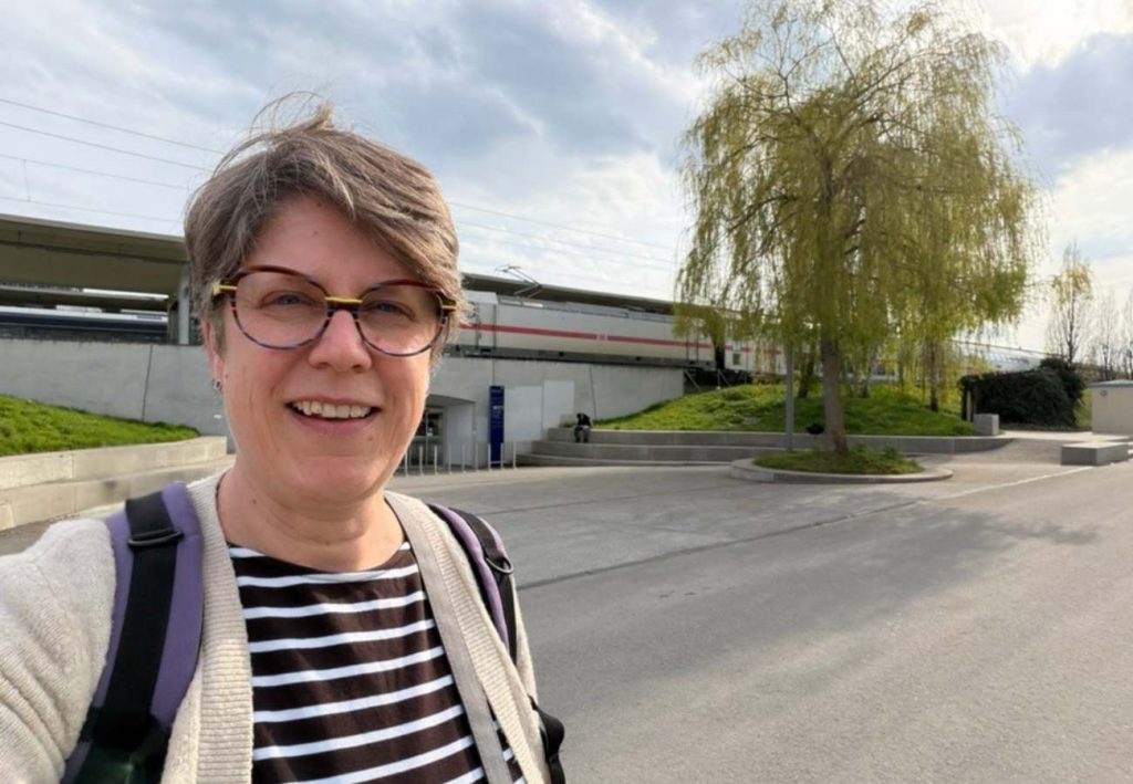 Sabine Landua im Hintergrund der Bahnhof mit durchfahrendem ICE