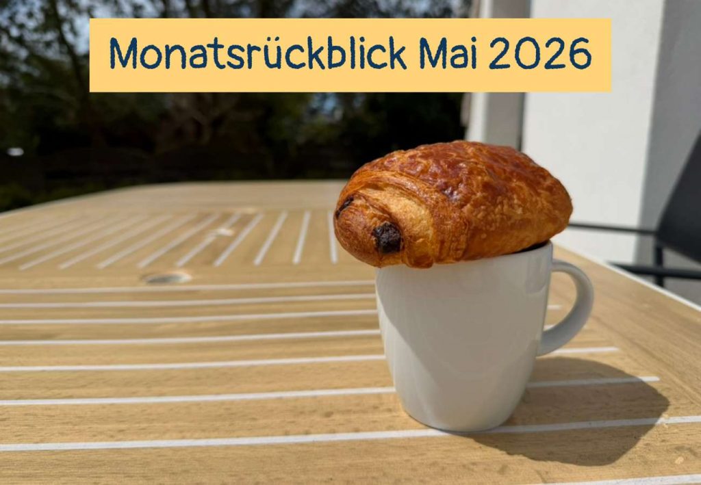 Eine Tasse mit einem Schokocroissant auf einem Terrassentisch, Text: Monatsrückblick Mai 2026