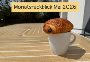 Eine Tasse mit einem Schokocroissant auf einem Terrassentisch, Text: Monatsrückblick Mai 2026