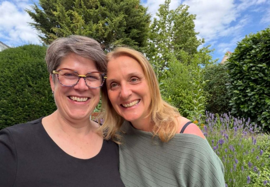 Zwei Freundinnen im Garten lachen in die Kamera
