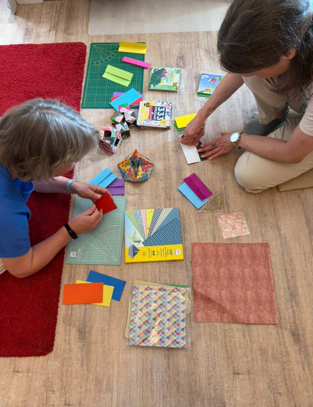 Zwei Frauen sitzen auf dem Boden und Falten Origami