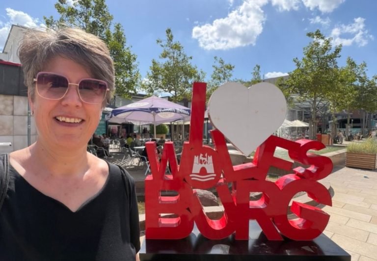 Sabine Landua in der Fußgängerzone vor dem Schriftzug I love Wolfsburg